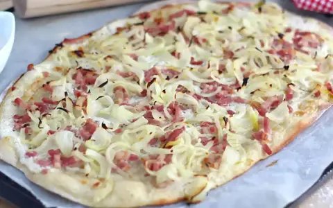 Flammekueche croustillante, garnie d'oignons et lardons. La vraie recette flammekueche, prête à être dégustée.