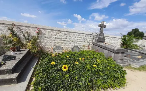 La tombe de Van Gogh, recouverte de verdure et ornée de tournesols, sous un ciel bleu.