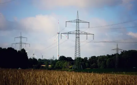 Wiatraki i linie energetyczne na tle nieba. OZE w Polsce to przyszłość, która już dziś zasila nasze domy.