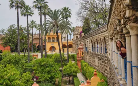 Ein Wahrzeichen von Sevilla: üppige Gärten, Palmen und eine Frau, die aus einem Säulengang schaut.