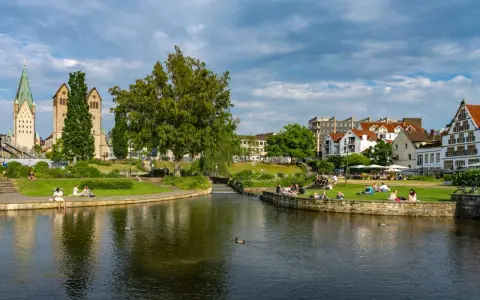 Entspannte Menschen genießen die Sonne am Flussufer in Paderborn. Ein schöner Ort für Paderborn Geheimtipps.