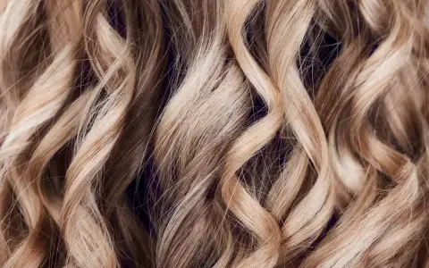 Falujące, blond włosy z subtelnymi refleksami, które mienią się w świetle, tworząc efekt głębi.