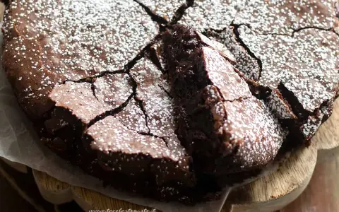Una deliziosa torta al cioccolato fondente, con una crosta crepata e cosparsa di zucchero a velo, pronta per essere gustata.