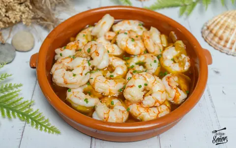 Gambas al ajillo burbujeantes en cazuela de barro, con perejil picado y un toque de aceite de oliva. ¡Un clásico irresistible!