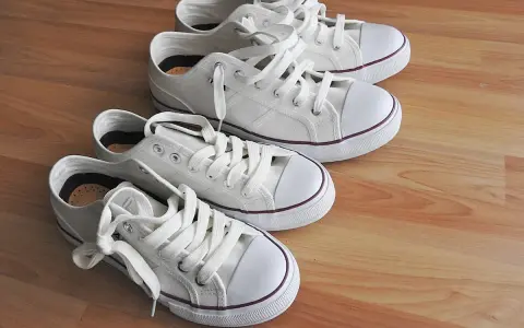 Cuatro zapatillas blancas de lona, listas para limpiar y lucir impecables.