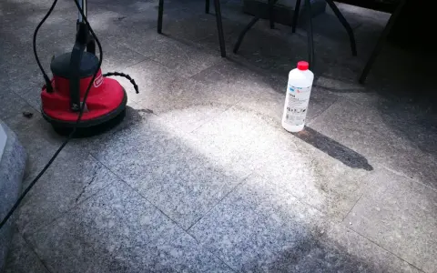 Czym czyścić granit płomieniowany? Na zdjęciu widać maszynę czyszczącą i butelkę z preparatem do czyszczenia kamienia.