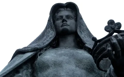 Statue de Jeanne la Folle, voilée, tenant une couronne de fleurs. Son regard est tourné vers le ciel.