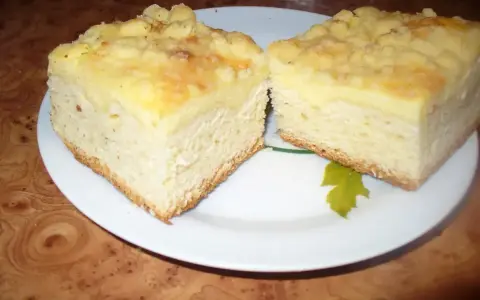 Dwa kawałki puszystego ciasta drożdżowego z serem i kruszonką, podane na talerzu.