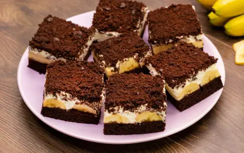 Saftiger Maulwurfkuchen vom Blech mit Bananen und Schokostreuseln auf einem rosa Teller.