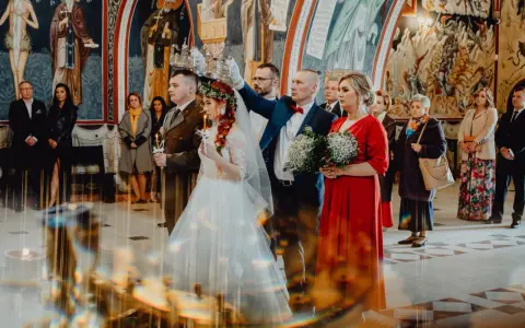 Para młoda podczas ceremonii ślubu prawosławnego. Pan młody w mundurze, panna młoda w bieli. Nad nimi trzymane są korony.