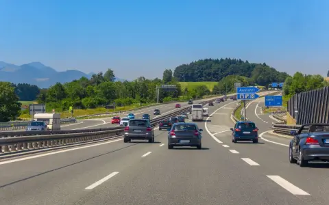 Trafik på en tysk motorväg med berg i bakgrunden. En skylt visar "Ausfahrt" (avfart), vilket indikerar en autohof i Tyskland.