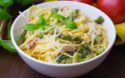 Pyszna carbonara ze szparagami, udekorowana bazylią i parmezanem, czeka na spróbowanie.