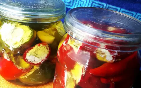 Słoiki z marynowanymi papryczkami nadziewanymi serem feta na zimę. Kolorowe papryczki w zalewie, gotowe do spożycia.