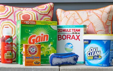 Supplies for how to clean outdoor cushions: Scotchgard, Gain detergent, Borax, baking soda, OxiClean, and a scrub brush.