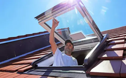 Mann installiert Dachfenster. Informieren Sie sich über Dachfenster Kosten und die Vorteile von mehr Licht.