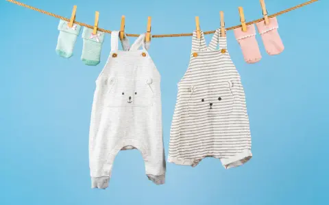 Ropa de bebé colgada para secar: dos peleles con caritas de oso y calcetines a juego. ¡El momento perfecto para saber cuando lavar la ropa del bebé!