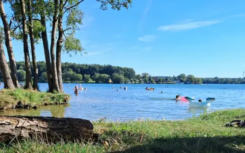 Słoneczny dzień nad jeziorem Pławniowice. Ludzie kąpią się i relaksują na dmuchanych zabawkach.