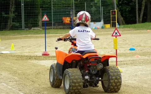 Chłopiec w kasku na quadzie uczy się zasad ruchu drogowego. To świetna kategoria pojazdów, czym można jeździć na specjalnych torach.