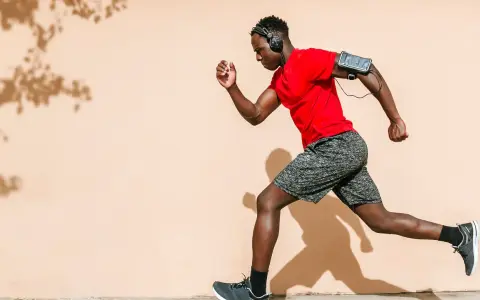 Hombre corre con audífonos y brazalete para celular. ¡Correr quema grasa y te da energía!