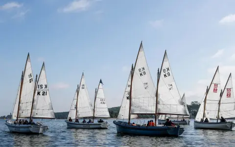 Segelboote mit weißen Segeln und Nummern wie "21" und "K9" auf dem Wasser, ein Teil der Veranstaltung "wm kiel".