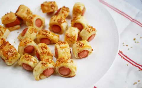 Une assiette de feuilleté saucisse dorés, parsemés de graines de sésame. Parfait pour un apéritif gourmand.