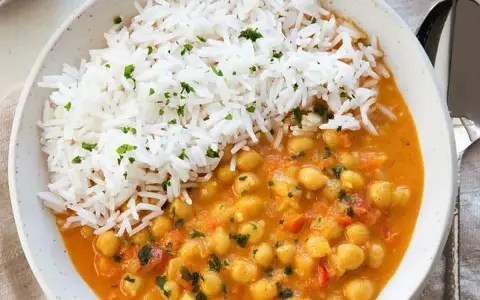 Un delicioso curry de garbanzos con arroz blanco esponjoso, espolvoreado con perejil fresco.