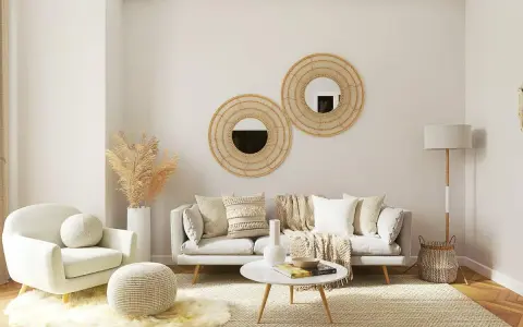 Salón acogedor con butaca blanca y sofá gris, decorado con espejos de mimbre y plantas secas. La combinación de sofá y butaca crea un espacio perfecto para relajarse.