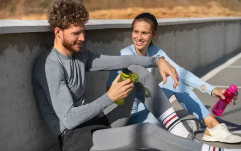 Ein Mann und eine Frau sitzen nach dem Sport und reden. Sie fragen sich, wie lange Pause nach Halbmarathon sinnvoll ist.