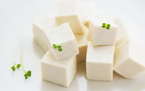 Kostki białego tofu, idealna podstawa do wielu dań, ozdobione świeżymi kiełkami.
