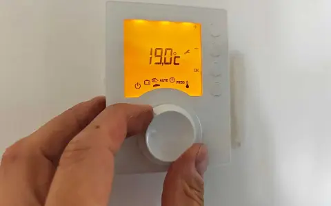 Main tenant ajuste le thermostat pour un mode confort, affichant 19.0°C.