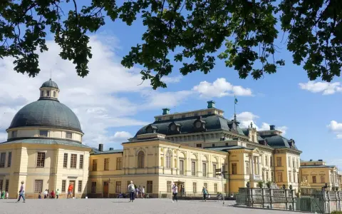 Drottningholms slott, där kungen bor, med sin imponerande kupol och gula fasader under en blå himmel med moln.
