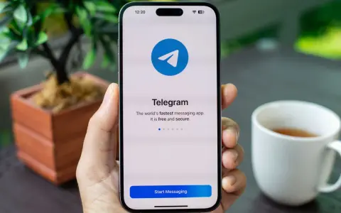 Dłoń trzyma smartfon z otwartą aplikacją Telegram. Na ekranie widnieje logo i napis "Telegram. The world's fastest messaging app. It is free and secure.