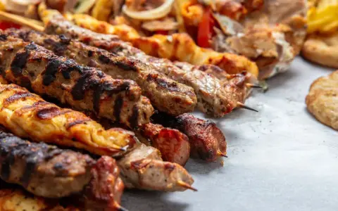 Grillowane szaszłyki z mięsem i warzywami, pyszna turecka potrawa, podane z chlebkiem pita i frytkami.