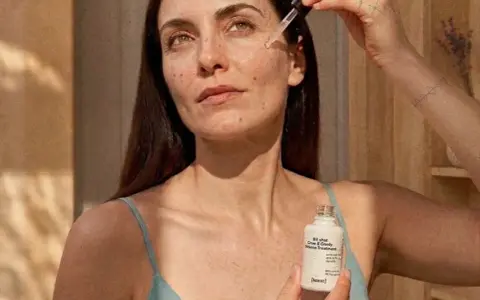 Kobieta aplikuje serum z niacynamidem i witaminą C na skórę. Delikatna pielęgnacja dla promiennej cery.