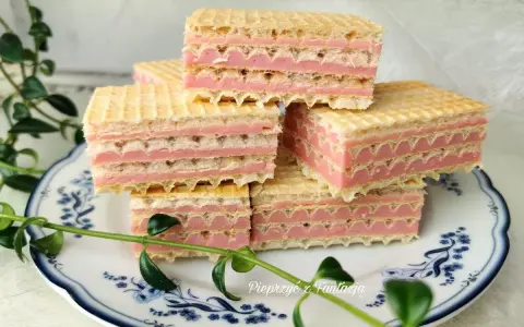 Piękne wafle z mlekiem w proszku, ułożone na talerzyku z niebieskimi wzorami, ozdobione zielonymi listkami.