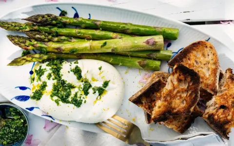 Burrata med sparris och rostat bröd, toppad med en fräsch gremolata. Perfekt för ett lätt sommarmål.