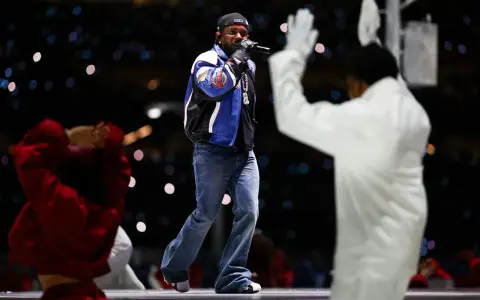 Un rappeur sur scène, micro en main, devant une foule lumineuse. Une performance qui rappelle l'énergie du rap francais.