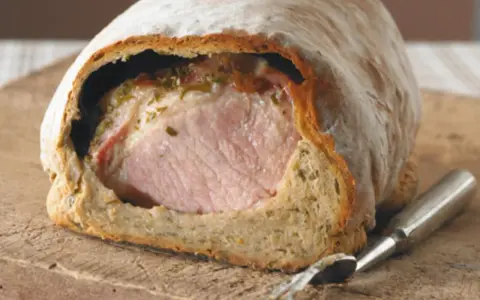 Saftiges Kassler im knusprigen Brotmantel, bereit zum Anschneiden. Ein Festmahl!