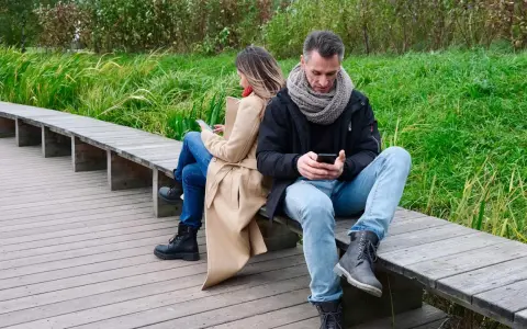 Para, siedząc tyłem do siebie na ławce, wpatruje się w telefony. Może szukają inspiracji, co napisać do dziewczyny, zamiast rozmawiać?