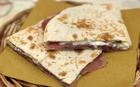 Piadine ripiene di prosciutto e formaggio, pronte per essere gustate dopo la cottura.