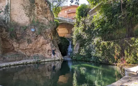 Un hombre posa junto a una cascada en un estanque natural en Ferez, Albacete.