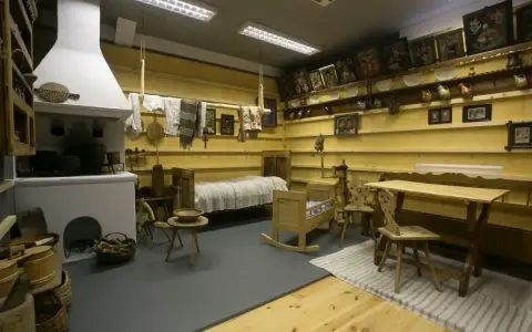 Wnętrze izby w muzeum w Szczawnicy: piec, łóżko, kołyska, stół i krzesła.