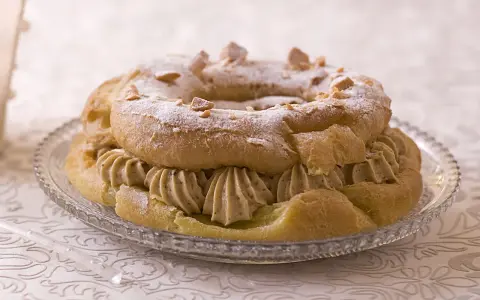 Un Paris-Brest, plat typique d'Île-de-France, garni de crème onctueuse et saupoudré de sucre glace et d'amandes.
