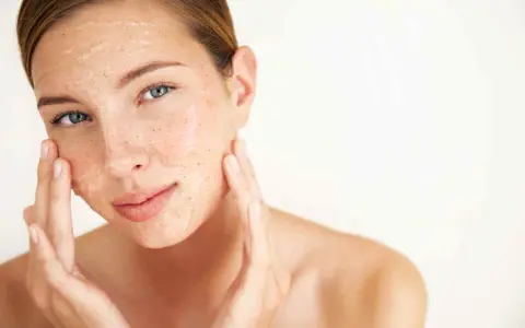 Mujer aplicándose una mascarilla exfoliante con vinagre de manzana para la cara. Sus dedos masajean suavemente el producto.