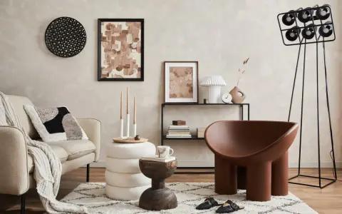 Przytulny salon z kanapą w tkaninie boucle, ozdobiony abstrakcyjnym obrazem i designerskim fotelem.
