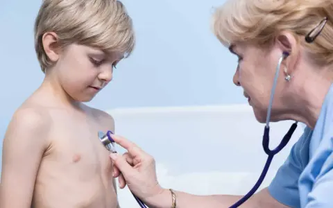 Lekarz osłuchuje klatkę piersiową chłopca, diagnozując zapalenie oskrzeli u dzieci.