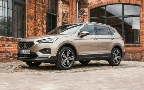 Beiger Seat Tarraco vor Backsteinhaus. Keine Seat Tarraco Probleme hier, nur stilvolles Fahren.