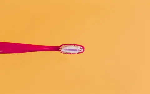 Różowa szczoteczka z pastą, która zawiera fluor. Czy fluor jest szkodliwy? Dyskusja trwa, ale pasta pomaga chronić zęby.