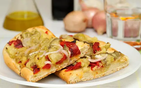 Dos porciones de coca de recapte con verduras asadas, pimientos rojos y cebolla.