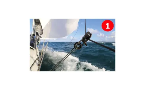 Le fonctionnement poulie est visible sur ce voilier naviguant sur une mer agitée. Les cordages tirent la voile blanche.